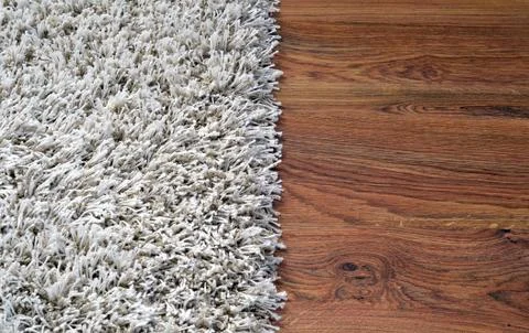Two part split image of white shaggy carpet and brown wooden floor Stock Photos