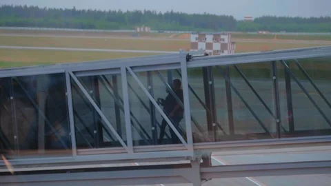 Two passengers boarding on airplane through a long glass airbridge. Video stock 97253350