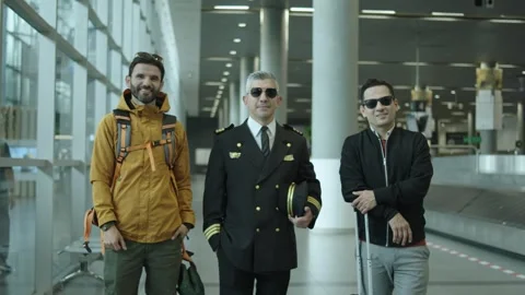 Two passengers pose with a pilot inside an airport building Stock Footage 306911692