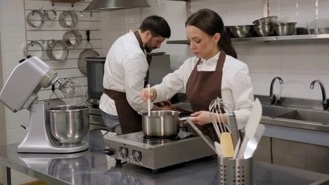 Two pastry chefs work in a pastry shop. Process of making a cake in the kitchen. Stock Footage 151410832