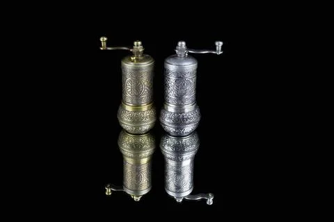 Two patterned silver pepperpots on black reflective surface Stock Photos