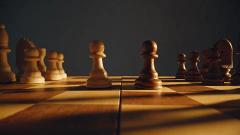Two pawns standing chessboard closeup. Chess pieces on sunlight checkered board Stock Footage 332336613