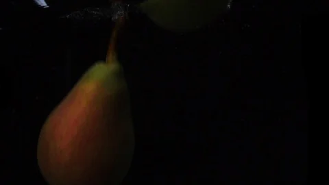 Two pears falls into the water with splashes and bubbles in slow motion. Video stock 105430076