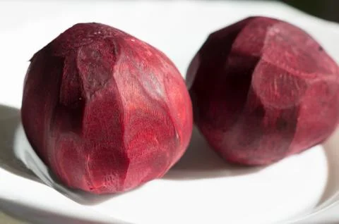 Two peeled beets that lying on the white plate. Stock Photos