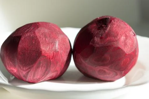 Two peeled beets that lying on the white plate. Stock Photos