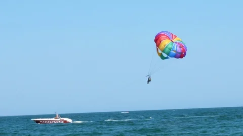 Two people in the air parasailing getting down from the air in the boat Stockbeeldmateriaal 94373215