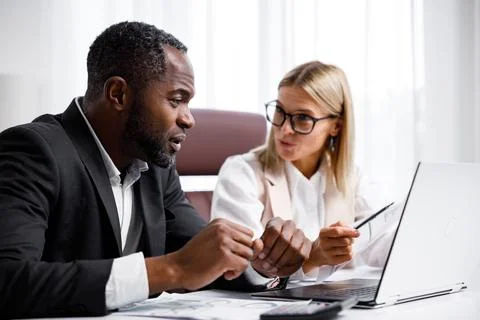 Two people analyze documents on a laptop while sitting at a table in the office Foto stock