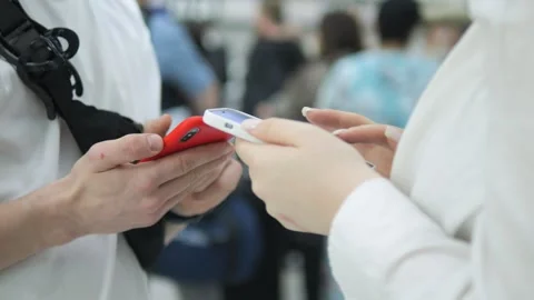 Two people are holding cell phones and one of them is red Stock Footage 311159348
