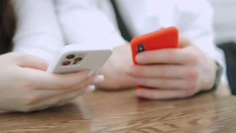 Two people are holding cell phones, one of which is a white iPhone Stock Footage 311395602