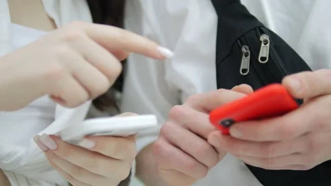 Two people are holding cell phones, one of which is red Stock Footage 312130139