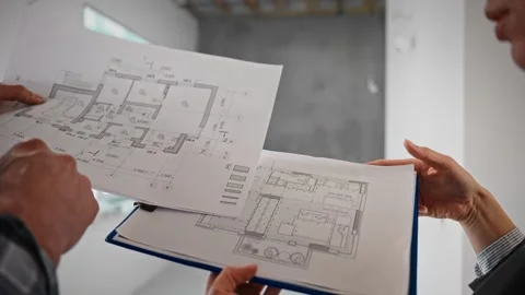 Two people are looking at a floor plan of a house Stock Footage 294162471