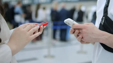 Two people are looking at their phones in a crowded airport Stock Footage 311384113