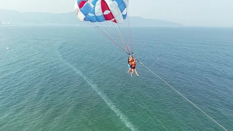 Two people are parasailing over the vast expanse of the blue ocean, elevated by 스톡 동영상 333376329