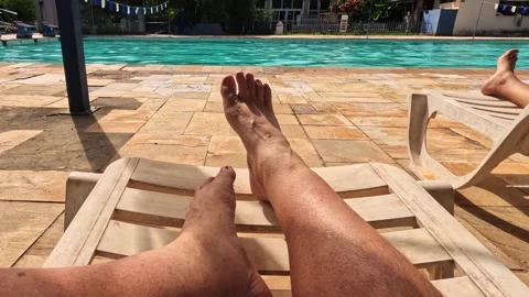 Two people are relaxing by the poolside, laying on loungers 스톡 동영상 330306614