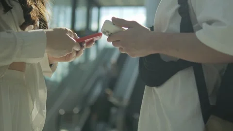 Two people are standing next to each other, one of them holding a red cell phone Stock Footage 311040234