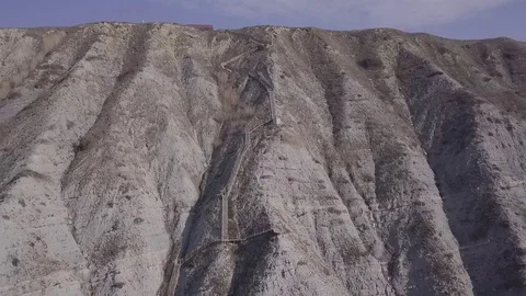 Two people are walking down stairs and seat at a beach near the cliffs Stock Footage 86902584