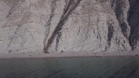 Two people are walking down stairs and seat at a beach near the cliffs Stock Footage 86902588