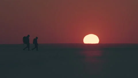 The two people with backpacks going through the field on sunset sky background Stock Footage 196285281
