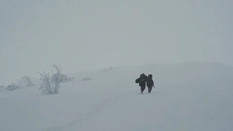 Two people climb a mountain in a winter snowstorm Stock Footage 292148447