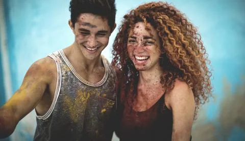 Two people covered in paint splatter and smiling. Stock Photos