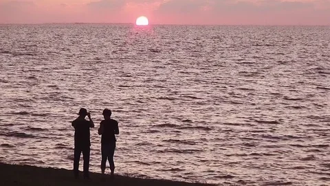 Two people on the dike looking to the sunset. Video stock 95438600