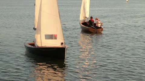 Two people in a dinghy sail in warm evening light Stock Footage