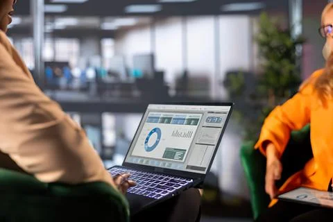 Two people discussing laptop with analytics charts Stock Photos