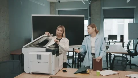 Two people discussing work tasks by a printer in an office setting Stock-Footage 330464515
