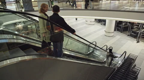 Two people down the escalator in the shopping centre Stockmann in St. Petersburg Stock Footage 63216089