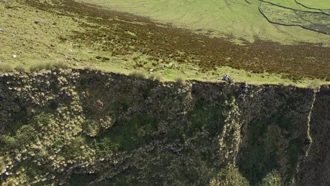 Two people on the edge of steep cliff look on huge caldera. Aerial of Caldeirao Stock Footage 119892032
