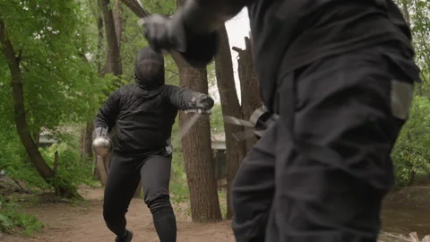 Two people engage in dynamic fencing match wearing black protective gear on Stock Footage 345836594