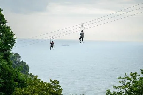 Two people experience thrill of ziplining, sliding along steel cable suspended Stock Photos