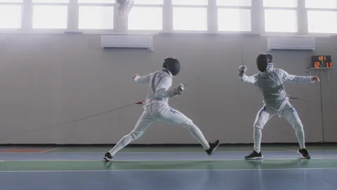 Two people fencing while using foil swords Stock Footage 274991291