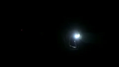 Two People with Flash Lights Walking Through a Mine Tunnel Видео 129177437