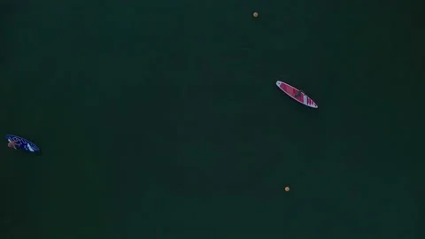 Two people float smoothly on the water of a lake and row with oars on SUP boards Stock Footage 170257355