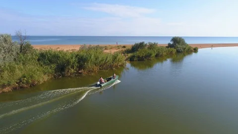 Two people floating in a motor boat on the river Stock Footage 98743026