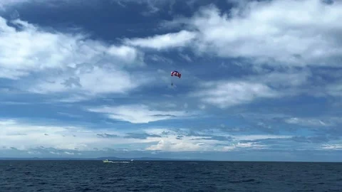 Two people fly on a parachute over a sky-blue sea on two domes towed by a boat Video stock 316548500