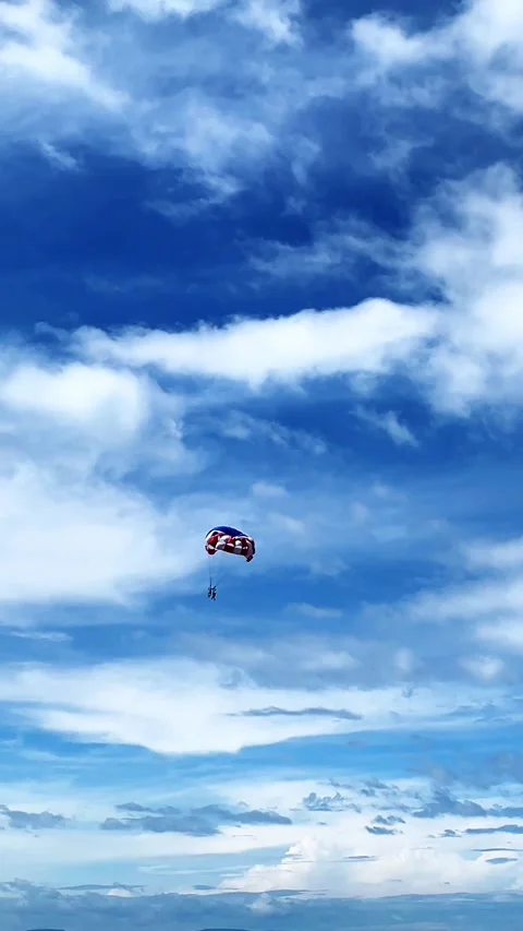 Two people fly on a parachute over a sky-blue sea on two domes towed by a boat Stock Footage 316548536