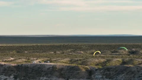 Two people flying over plain desert area at sunset Stock Footage 285146125