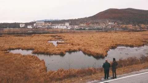 Two people gaze at the lake surrounded by mountains under the clear sky Stock Footage 274828764