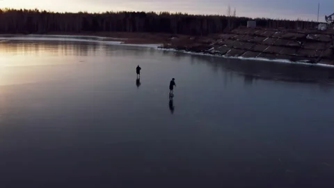 Two people go ice skating on a frozen lake in the morning Stock Footage 144251014