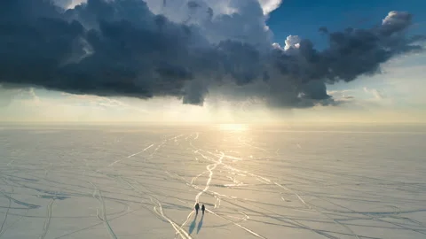 The two people going trough the snow field on the dark cloud background Video stock 189397239
