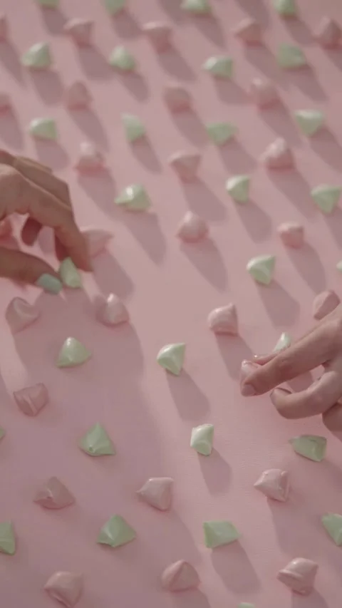 Two people hands picking small candies from pink surface Stock Footage 331778924