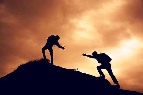 Two people  help each other on top of a mountain climbing team Stock Photos
