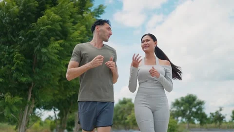 Two people jog side by side through a park Vídeo Stock 345216362