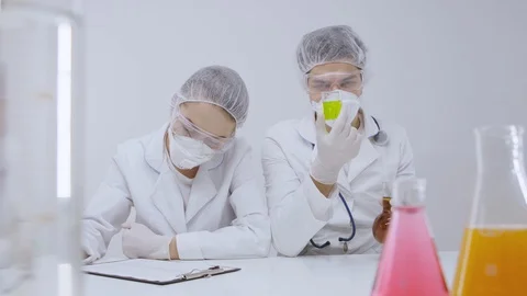 Two people in laboratory examine flasks with liquids 動画素材 129855160