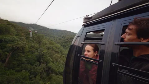 Two People Lean From Cable Car Window Looking Toward Forested Mountains in Dynam Stock Footage 323647714