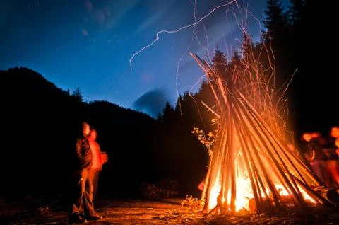 Two people looking at a campfire at night Stock Photos