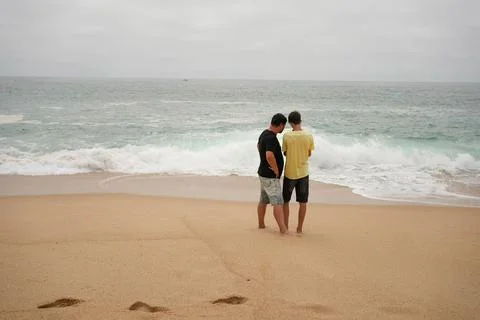 Two people looking at the waves of the ocean Stock Photos
