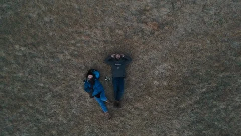 Two people lying in winter grass - zoom out Stock Footage 107882373